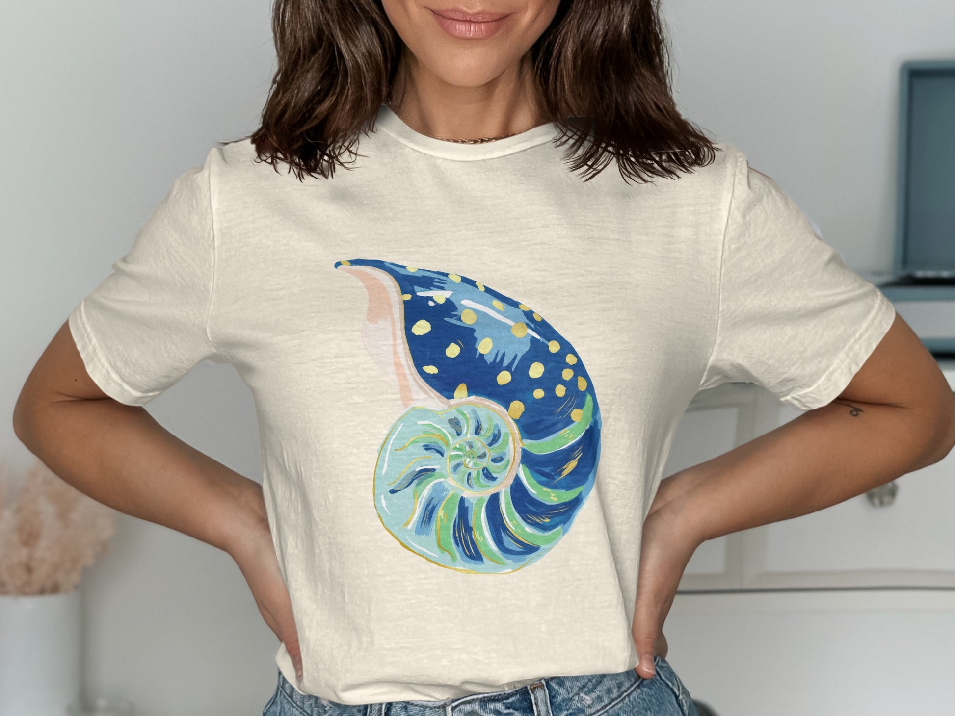 Cream t-shirt with a colorful spiral seashell graphic with yellow dots.