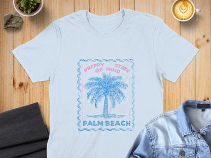 Light blue t-shirt with a pink and blue palm tree graphic and text.
