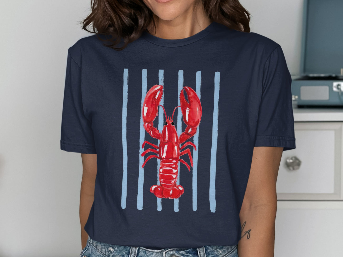 Navy t-shirt with a red watercolor lobster illustration on vertical blue stripes.