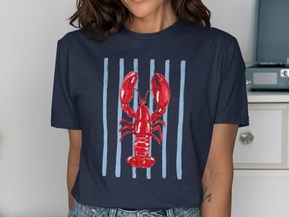 Navy t-shirt with a red watercolor lobster illustration on vertical blue stripes.