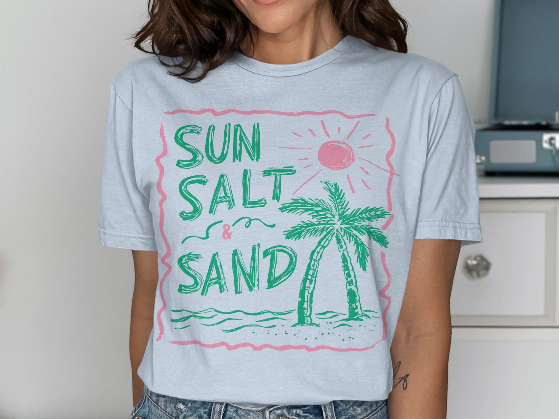 Light blue t-shirt with pink graphic: SUN SALT & SAND, palm tree, and sun.