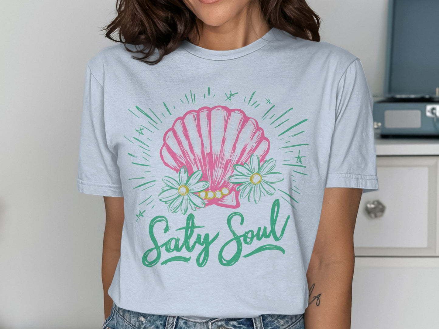 Light blue t-shirt with pink seashell, daisies, and "Salty Soul" text.