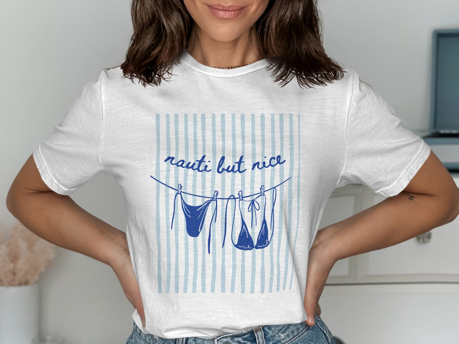 White t-shirt with "nauti but nice" and bikini hanging on clothesline.