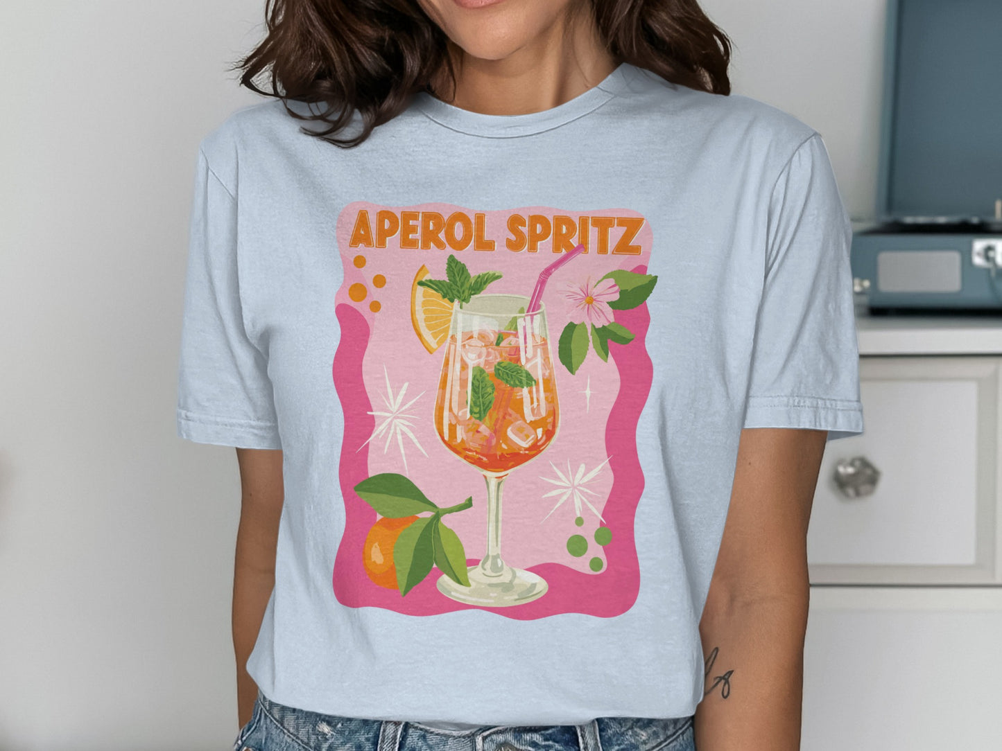 Light blue t-shirt with "Aperol Spritz" text and illustrated cocktail.