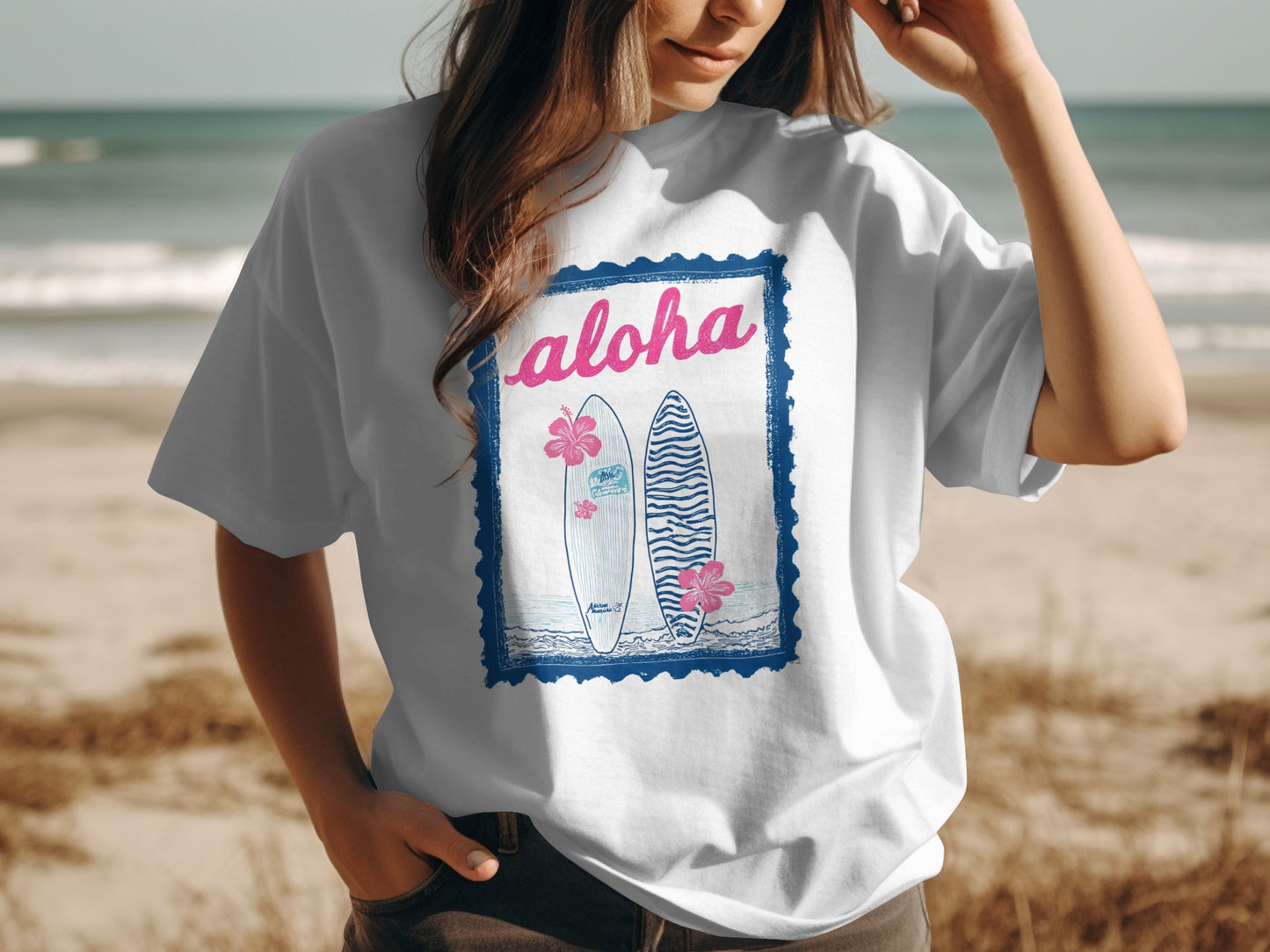 White t-shirt with "Aloha" text and two surfboards, framed by a blue border.