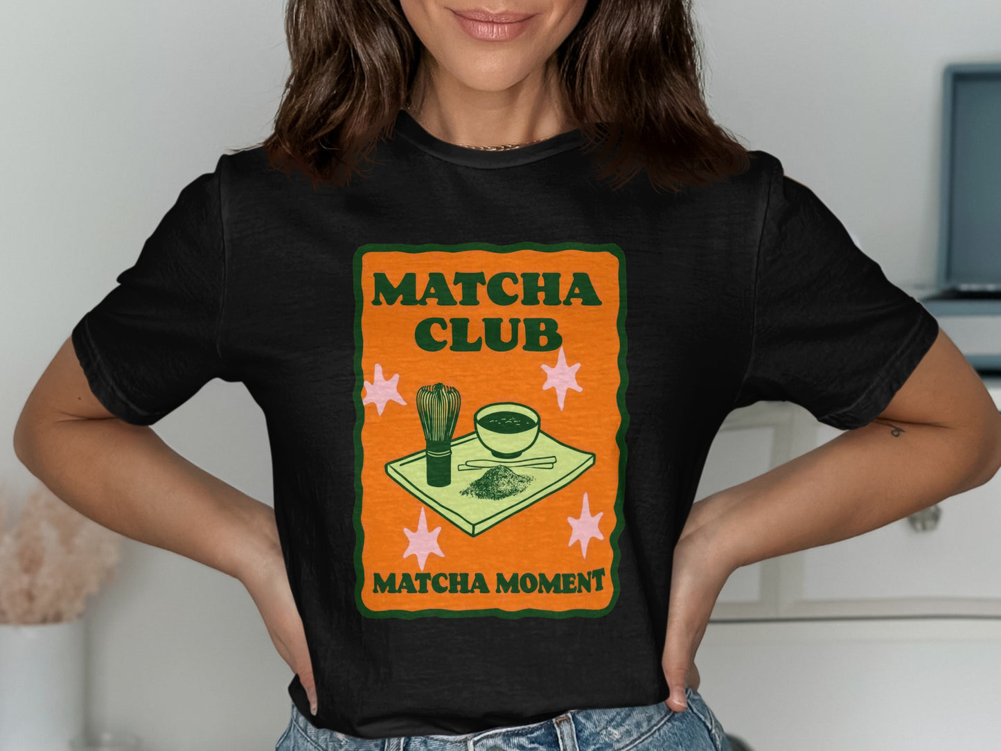 Black t-shirt with orange and green "Matcha Club Matcha Moment" text and matcha tea set illustration.