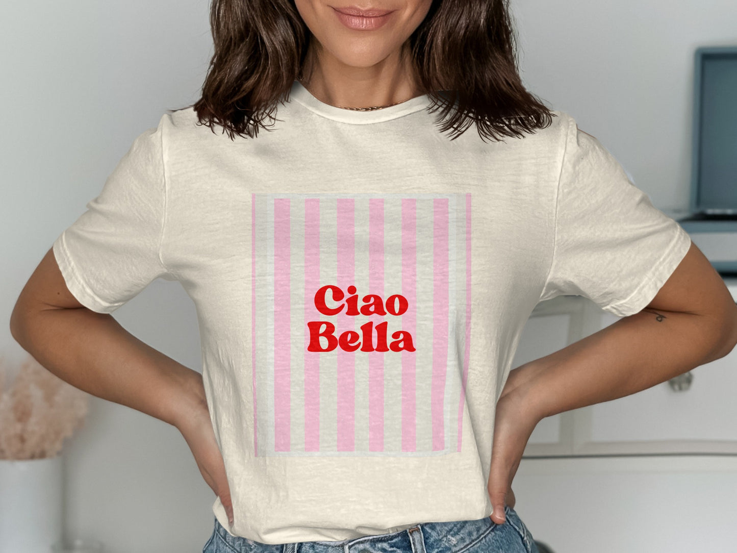 Cream t-shirt with "Ciao Bella" in red text on a pink and white striped background.