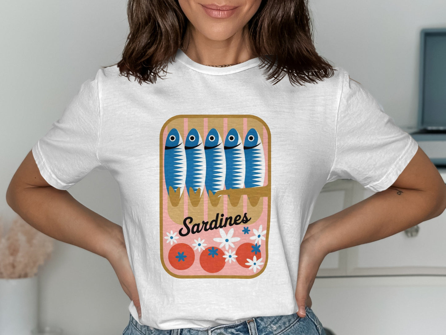 White t-shirt featuring a cartoon sardine can with blue sardines and tomatoes.