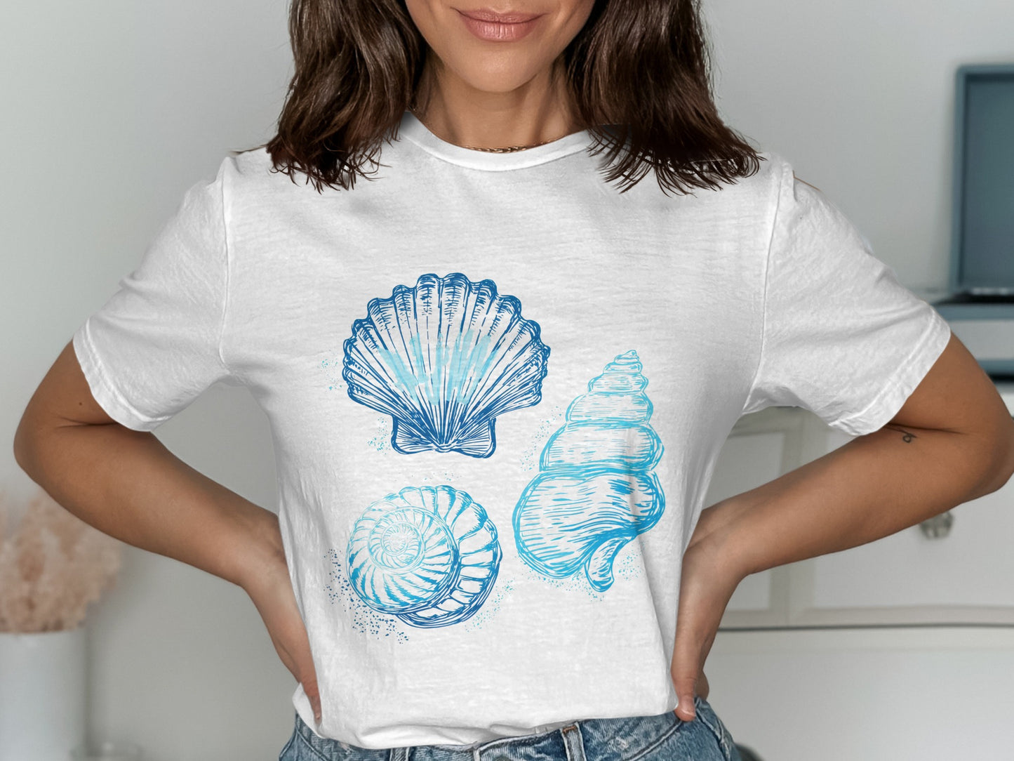 White t-shirt with three blue watercolor seashell illustrations.