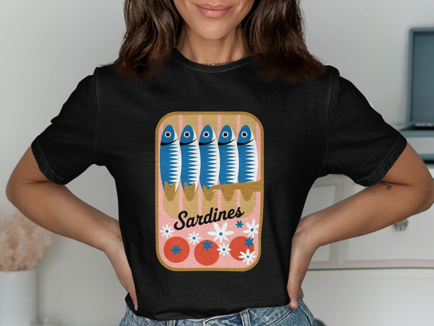 Black t-shirt with a cartoon can of sardines, tomatoes, and flowers.