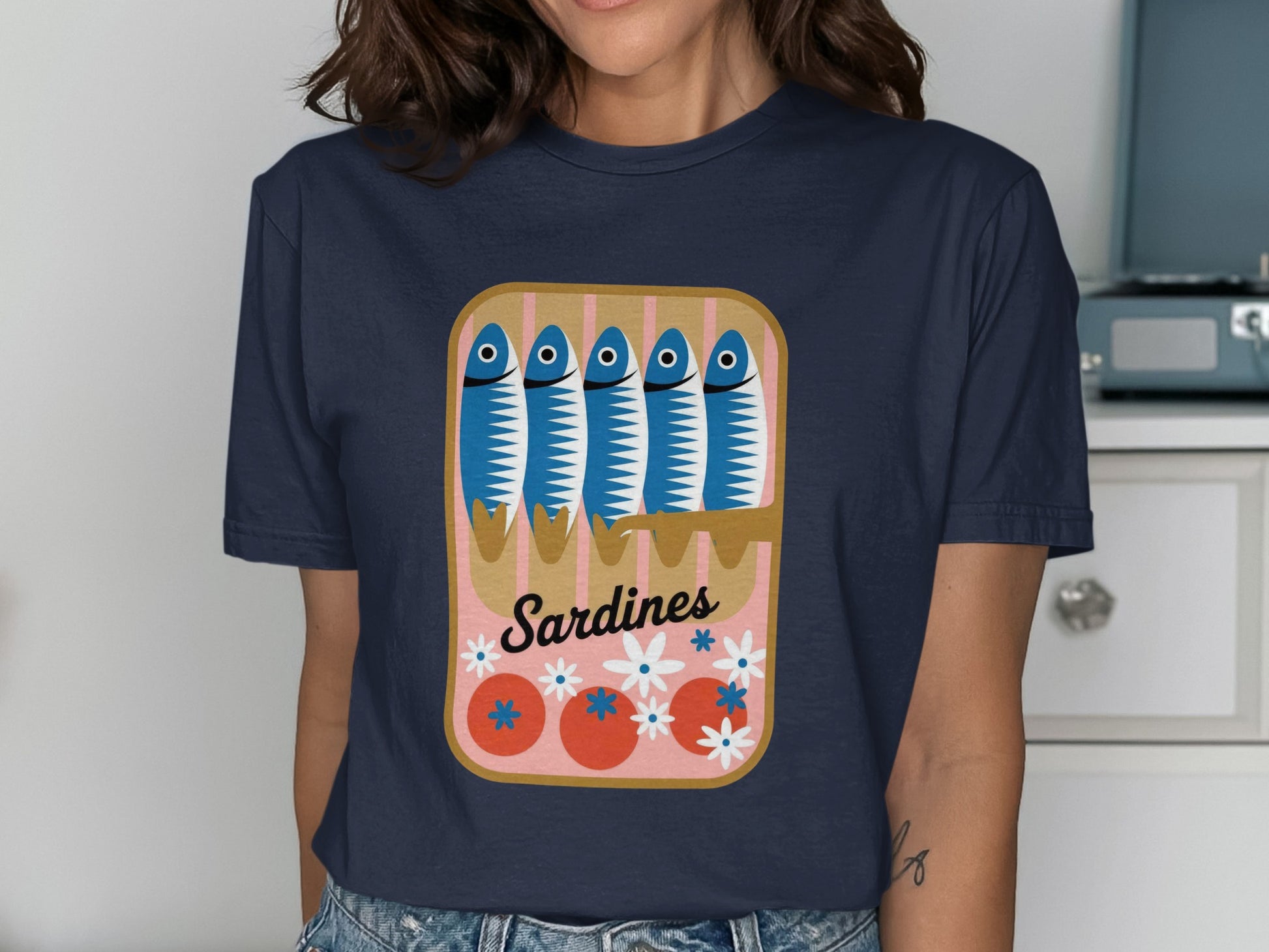 Sardines in a can with tomatoes and flowers graphic on a navy t-shirt.