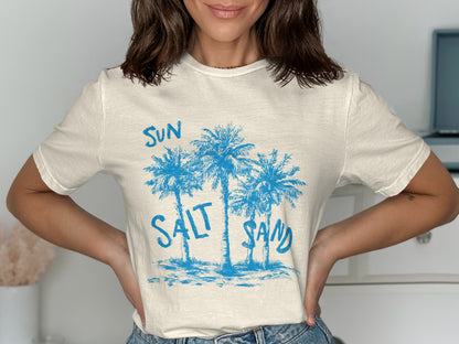 Cream t-shirt with blue palm trees and "SUN SALT SAND" text.
