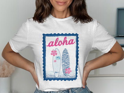 White t-shirt with "Aloha" text and two surfboards in a blue frame.