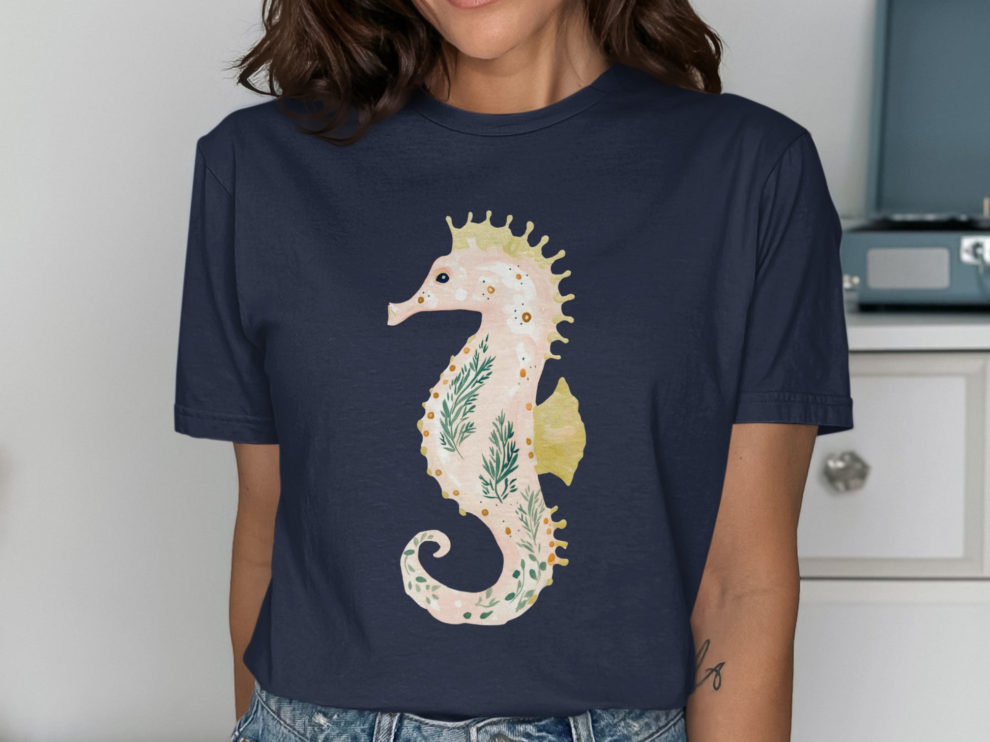Navy t-shirt with a light pink seahorse graphic featuring green leafy accents.