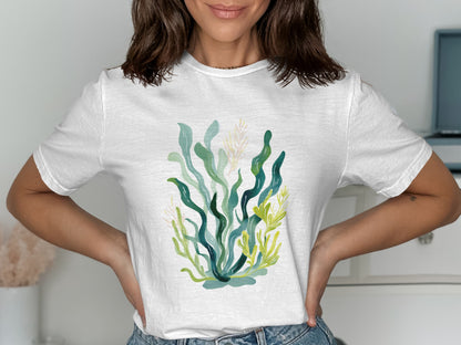 White t-shirt with watercolor illustration of green seaweed and yellow plants.