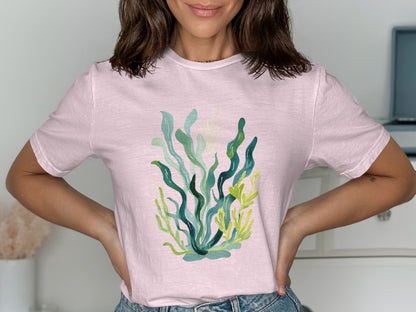 Pink t-shirt with a watercolor illustration of green and yellow seaweed.
