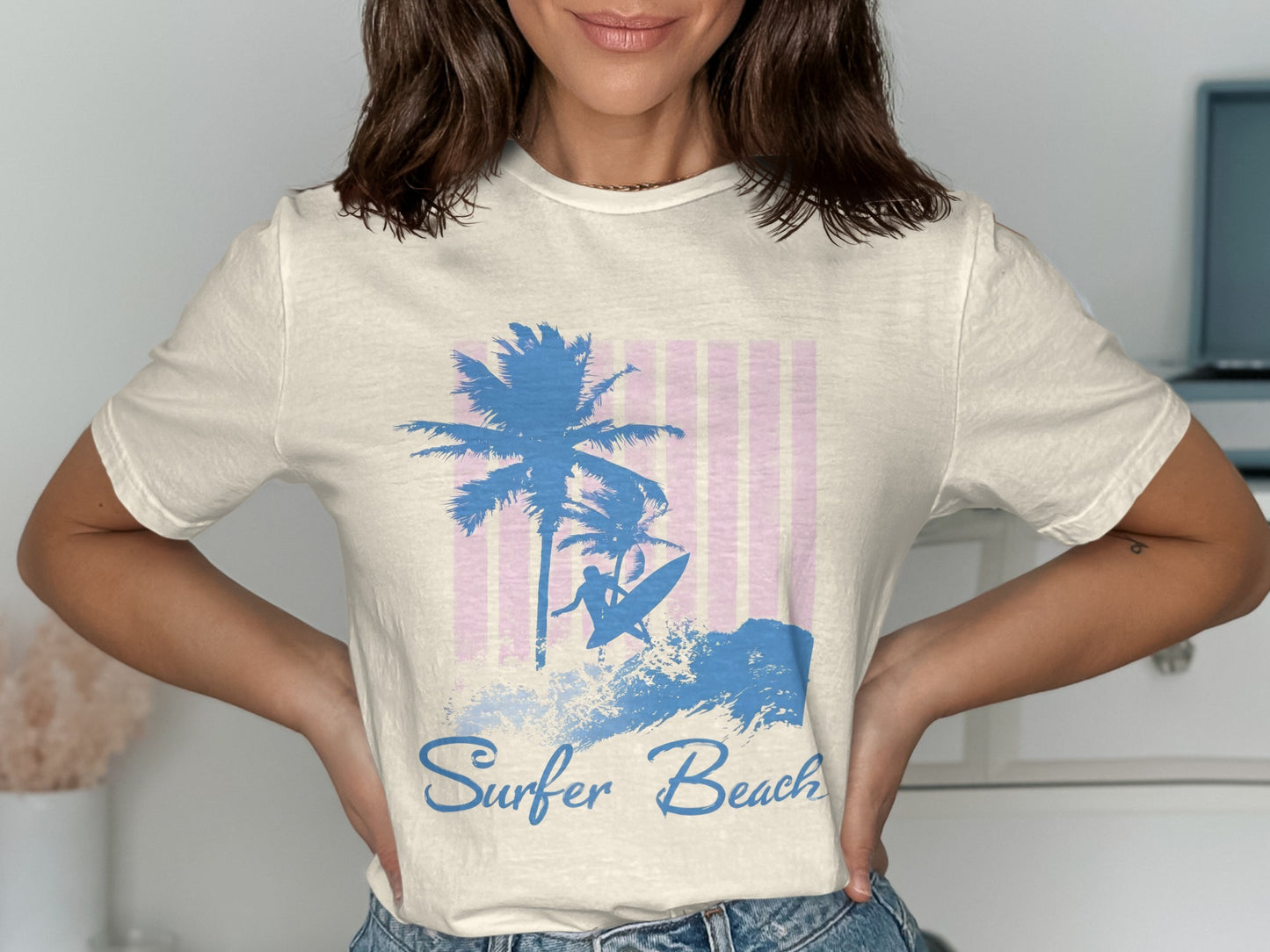 T-shirt with blue palm trees and surfer graphic on pink striped background.