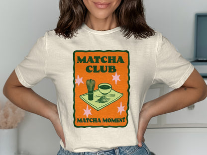 "Matcha Club Matcha Moment" text on a cream t-shirt with matcha bowl and whisk graphic.