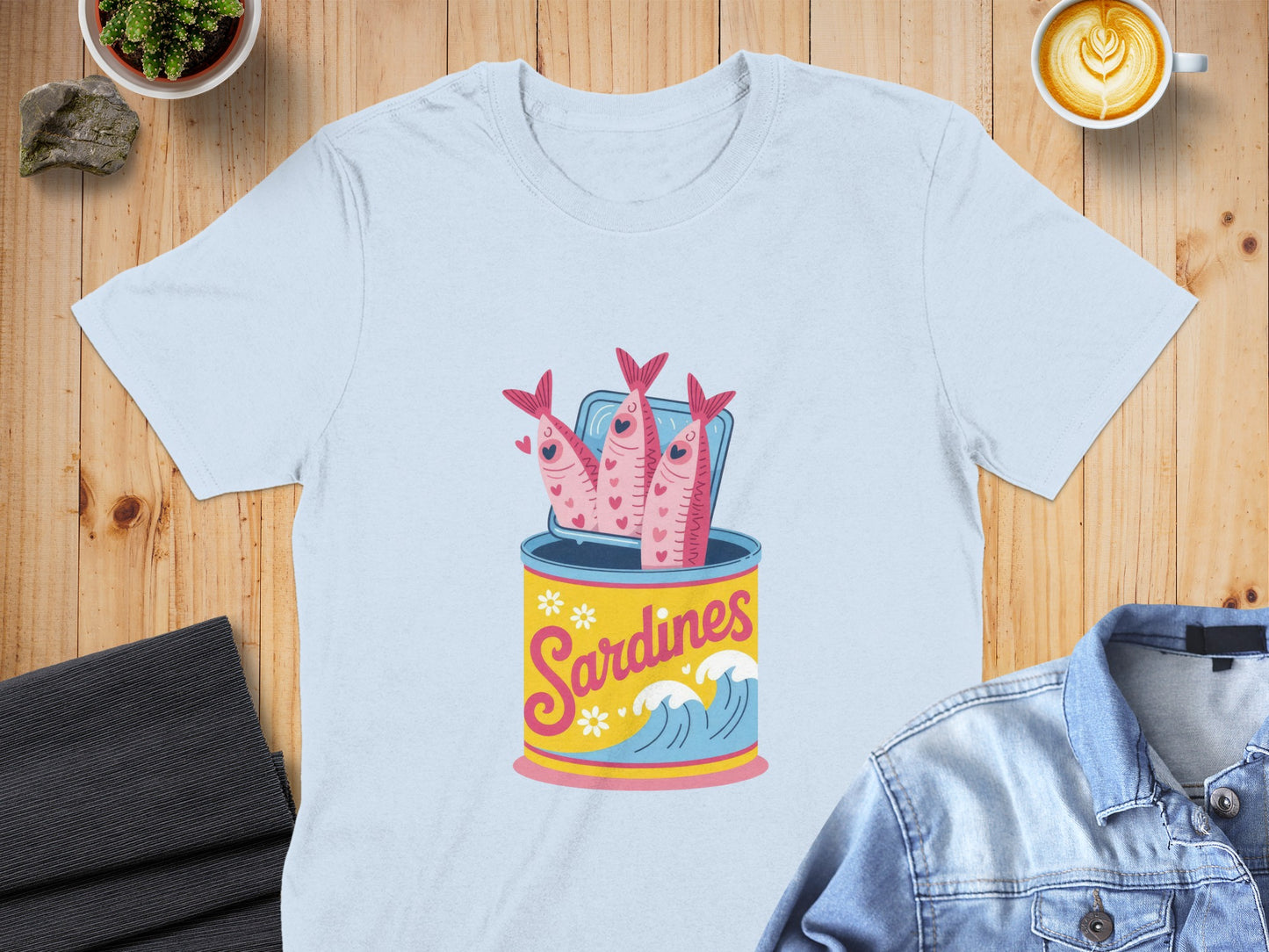Light blue t-shirt with a cartoon can of sardines illustration.