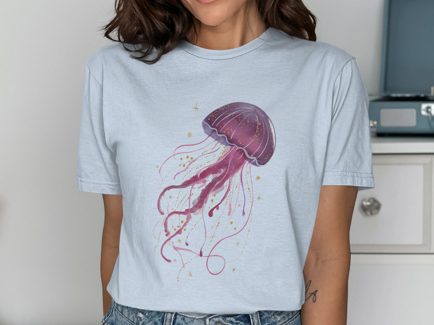 Light blue t-shirt with a purple jellyfish design with gold accents.