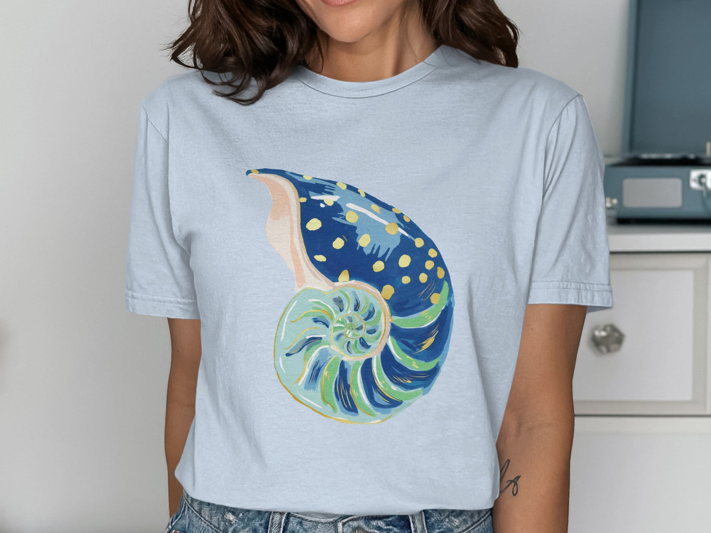 Light blue t-shirt featuring a painted nautilus shell design.