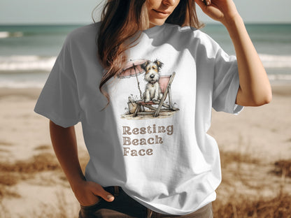 T-shirt with a dog sitting under an umbrella on a beach, text reads "Resting Beach Face".