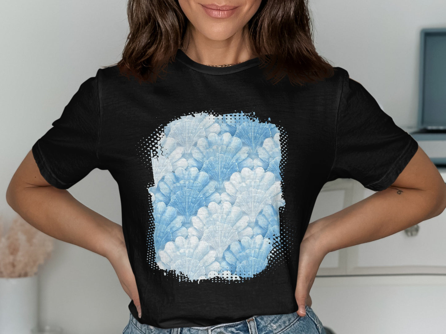 Black t-shirt featuring a watercolor seashell pattern in shades of blue.