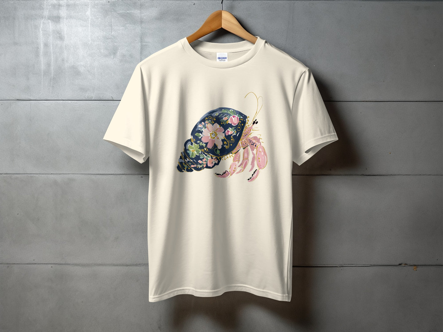 Cream t-shirt with a watercolor hermit crab and floral design.