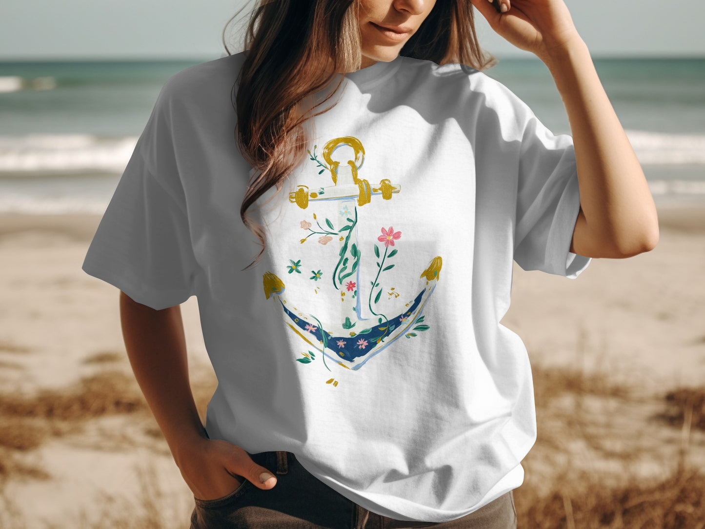 White t-shirt with floral anchor design on a beach background.