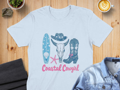 Light blue t-shirt with "Coastal Cowgirl" design: surfboard, skull, cowboy hat, boots.