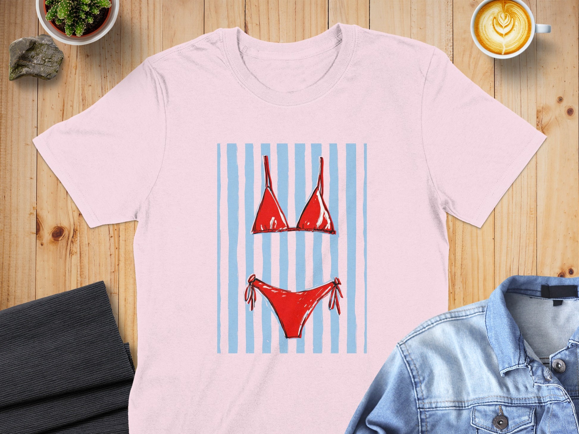 Pink t-shirt featuring a red bikini with blue stripes graphic.