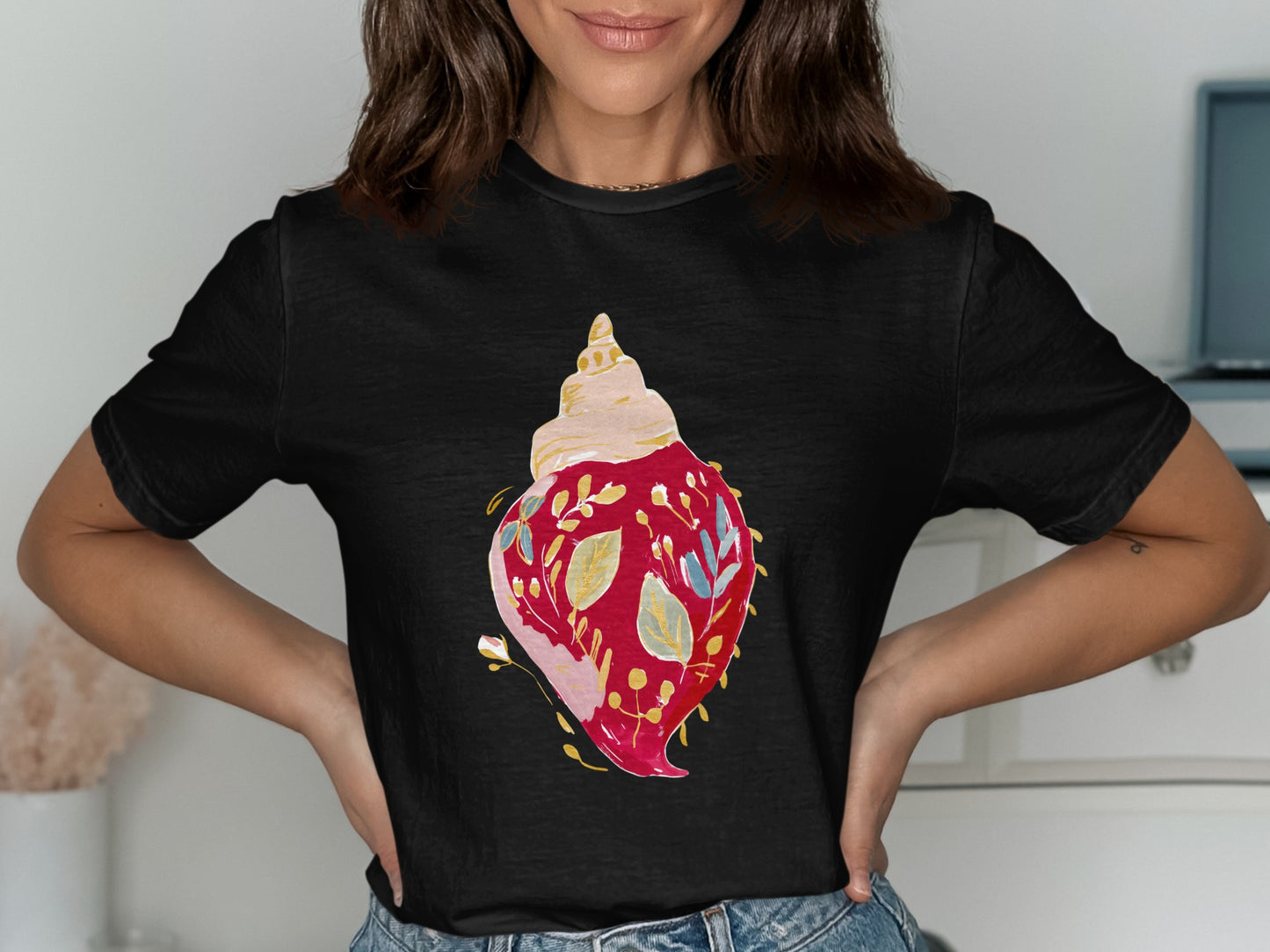 Black t-shirt with a colorful seashell graphic adorned with floral and leaf designs.