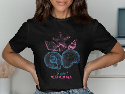 Black t-shirt with pink and blue seashells and starfish graphic and text.