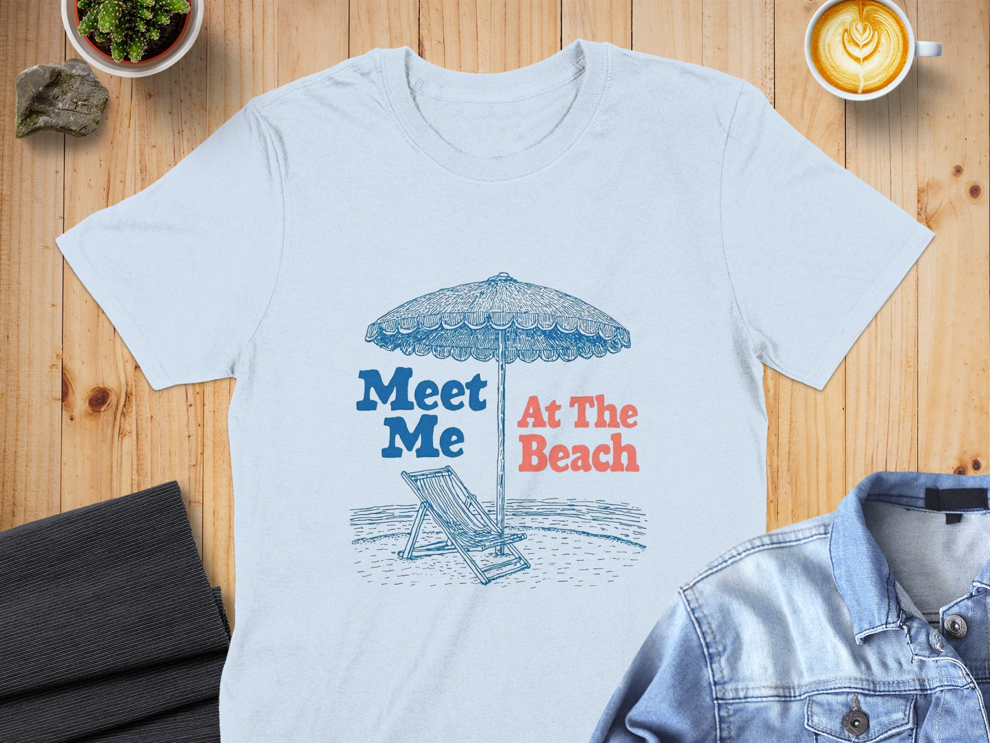 Light blue t-shirt with "Meet Me At The Beach" text and beach umbrella graphic.
