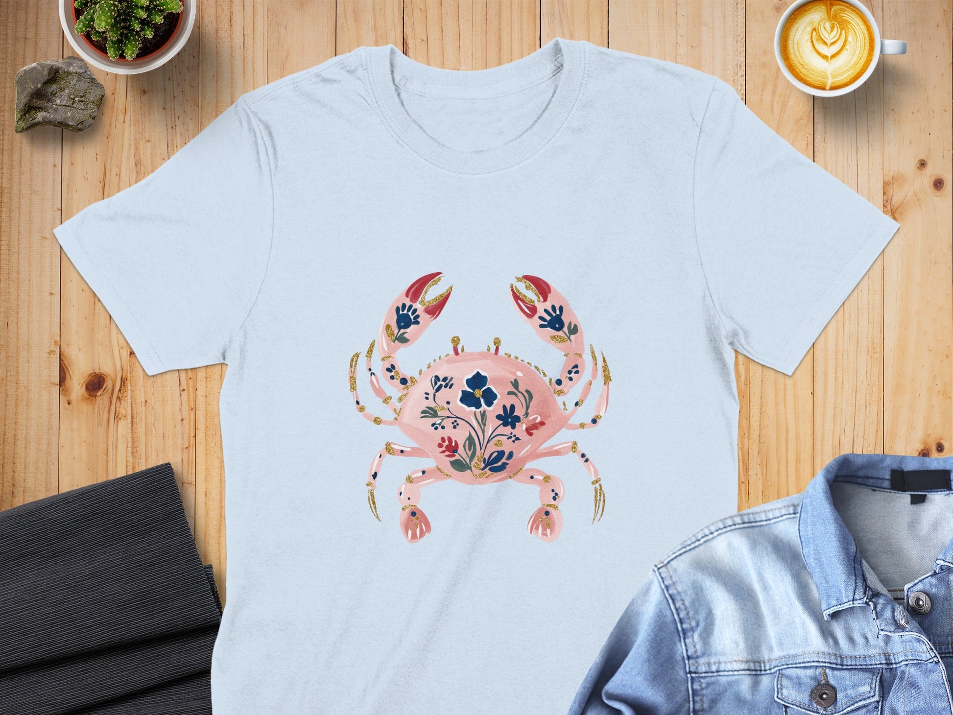 Light blue t-shirt with a pink crab graphic and floral embellishments.
