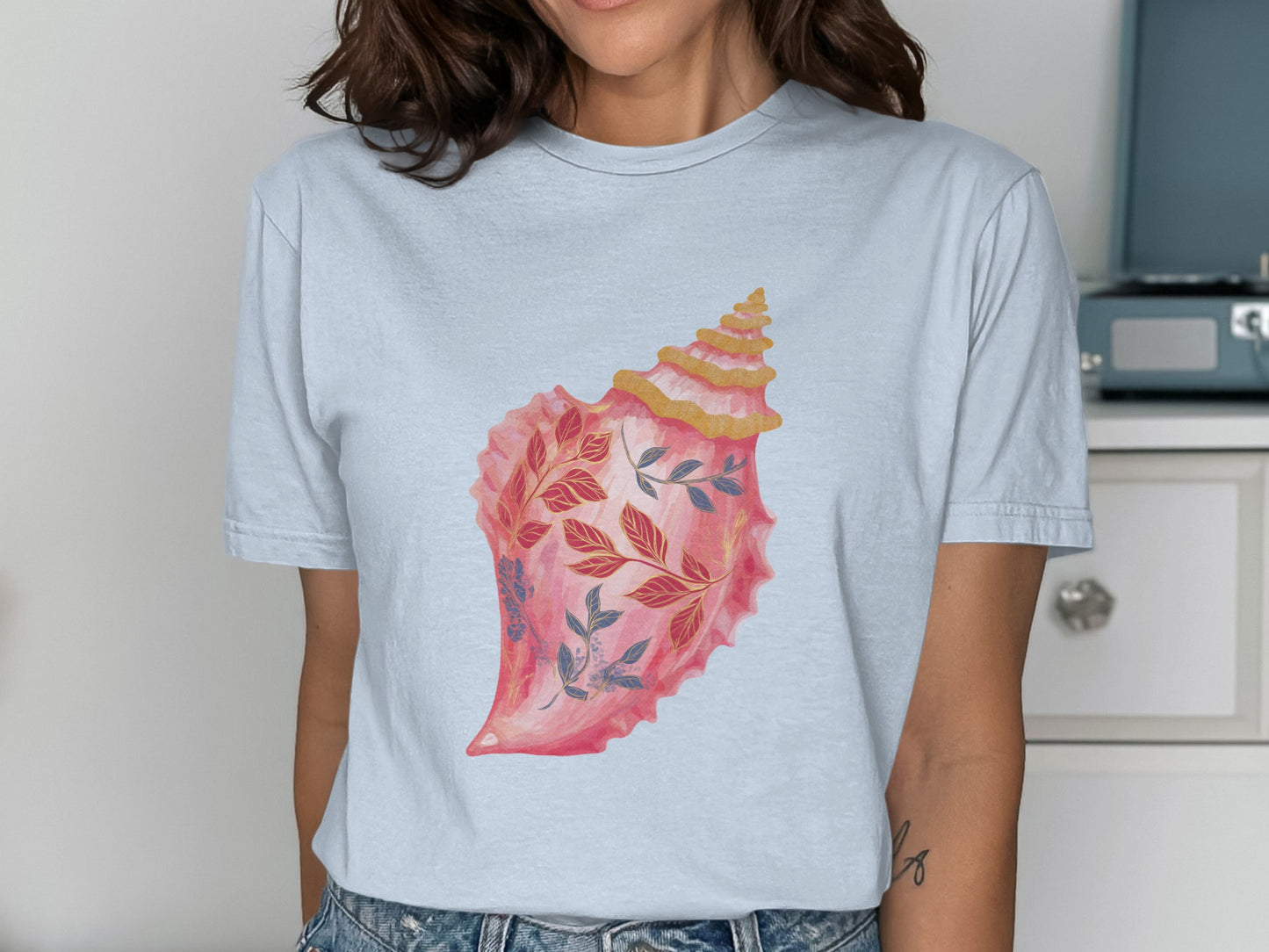 Pink and gold seashell with blue and red floral design.