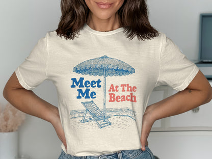 Cream t-shirt with blue and red text "Meet Me At The Beach" and beach illustration.