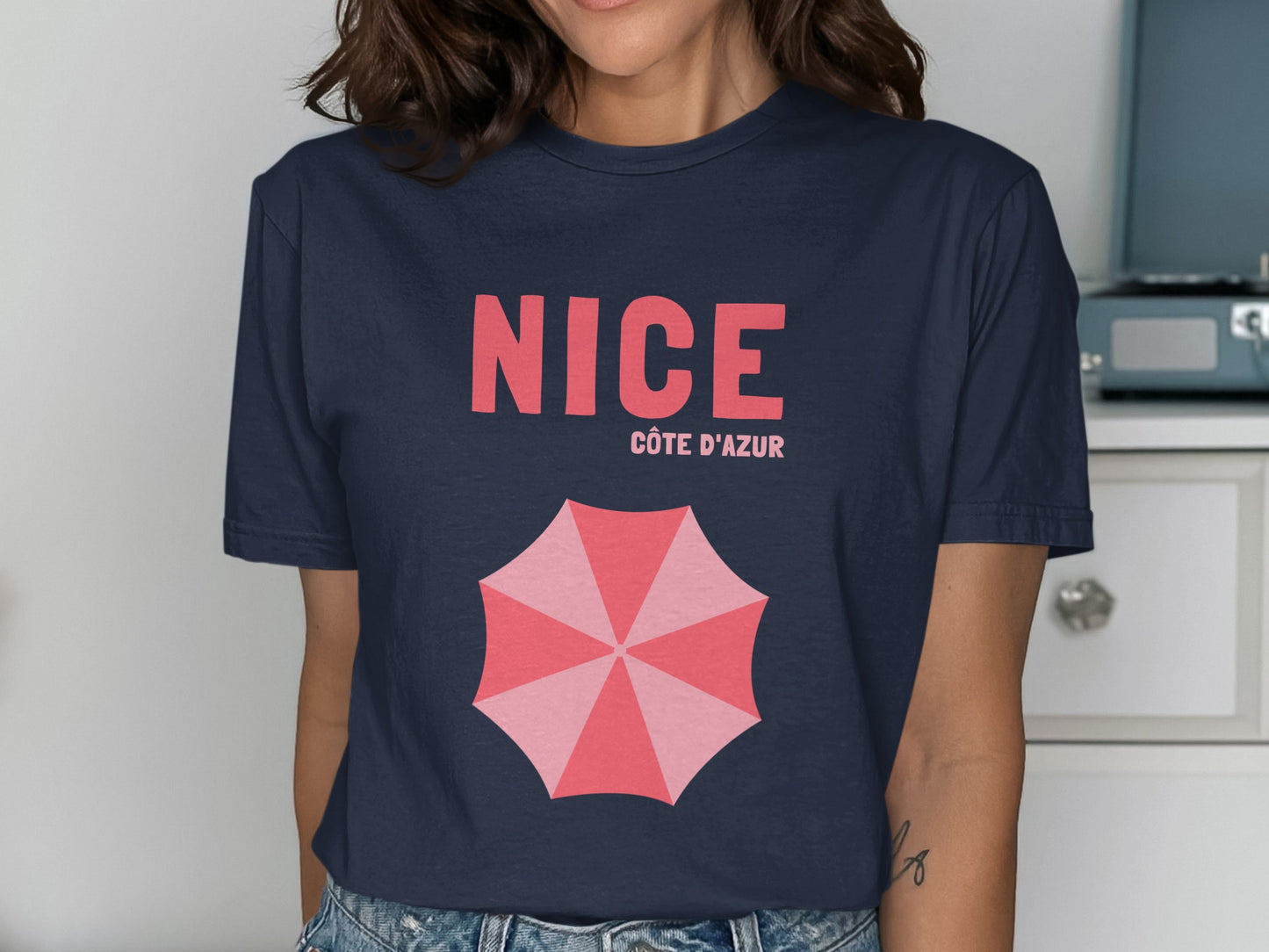 Navy t-shirt with "NICE CÔTE D'AZUR" and pink umbrella graphic.