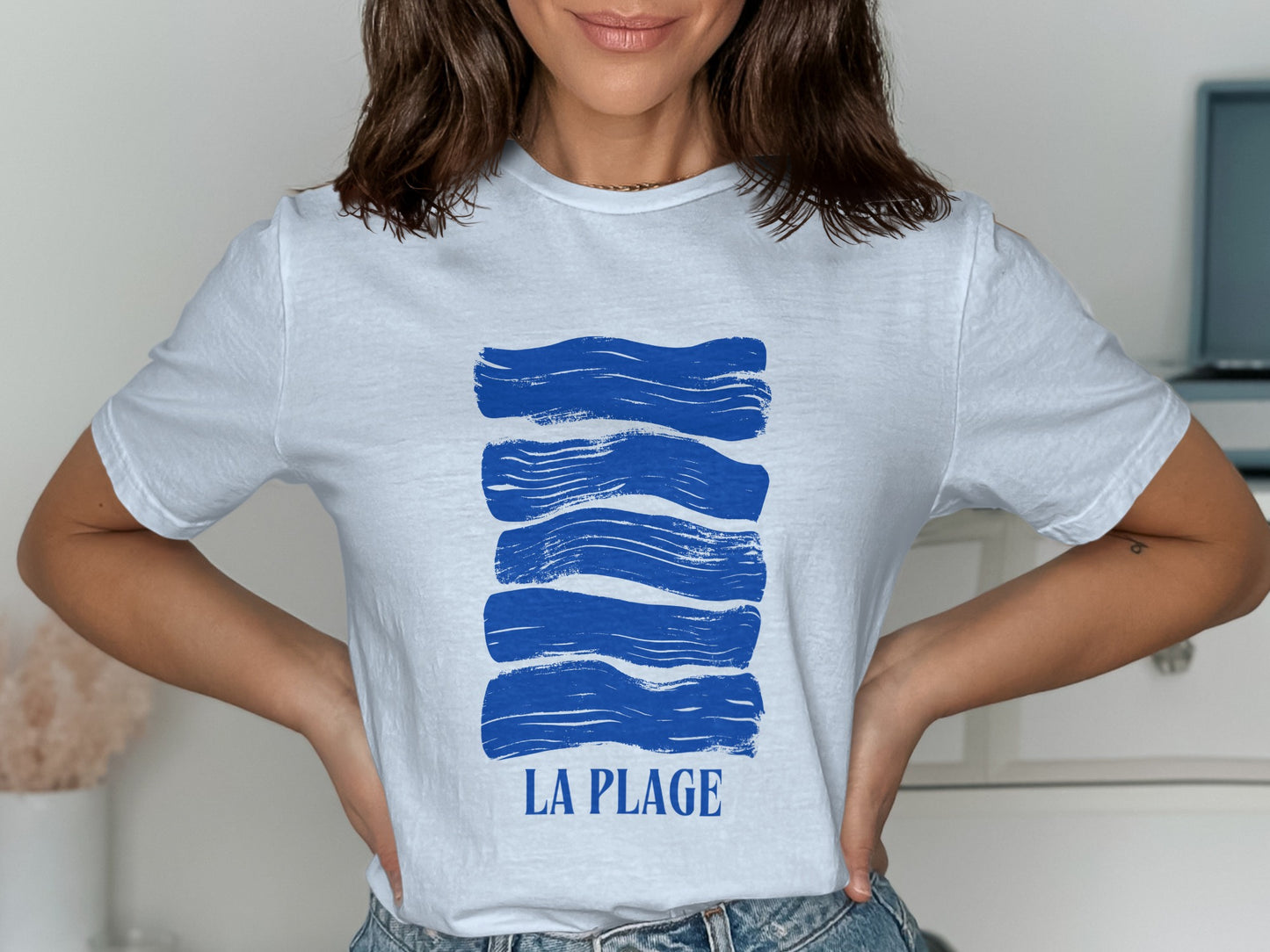 White t-shirt with horizontal blue brush strokes and "LA PLAGE" text.