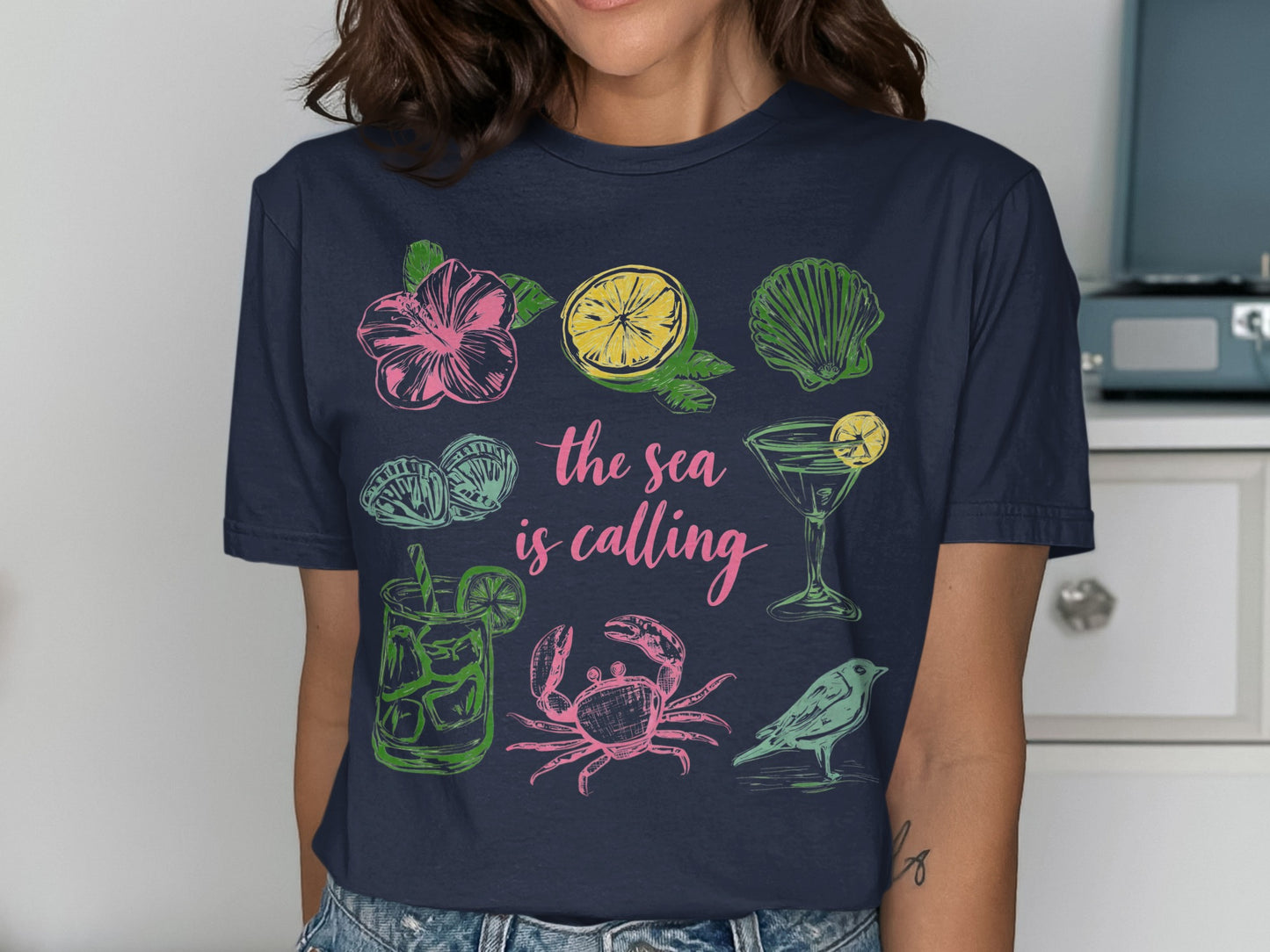 Navy t-shirt with "The sea is calling" text and beach-themed illustrations.