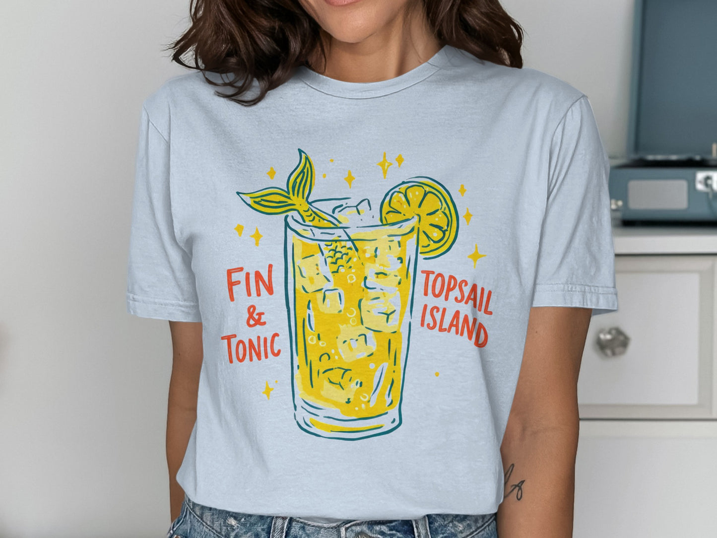 T-shirt graphic: mermaid tail in a "Fin & Tonic" cocktail with lemon