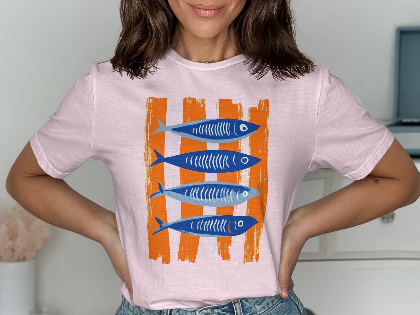 Pink t-shirt with four blue fish on orange striped background.