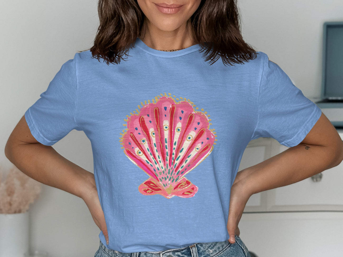 Light blue t-shirt with a pink and gold ornate seashell graphic.