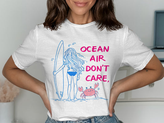 White t-shirt with blue line drawing of a surfer girl, surfboard, and crab.