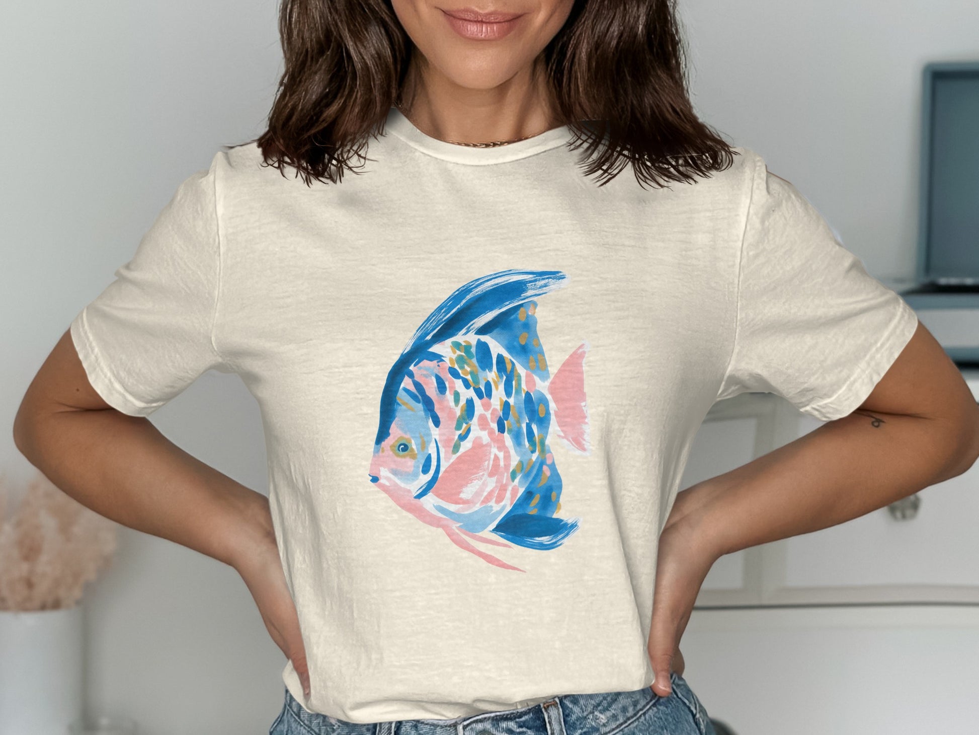 Cream t-shirt featuring a stylized, colorful blue and pink fish illustration.