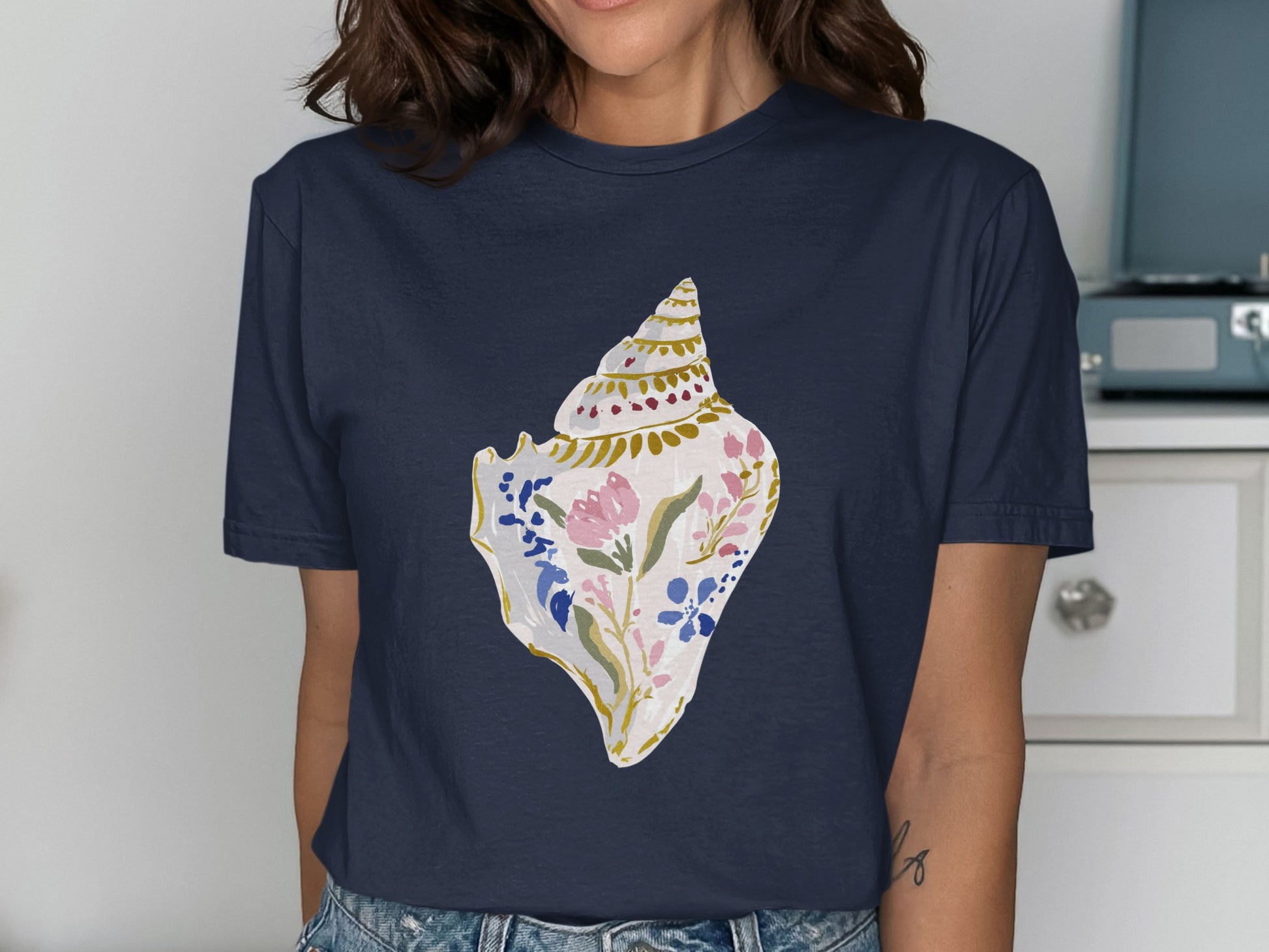 Dark blue t-shirt with a watercolor seashell graphic featuring pink and blue flowers.