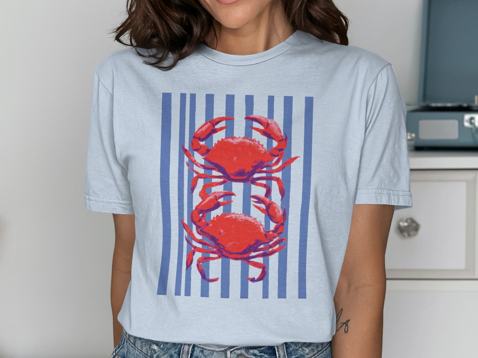 Light blue t-shirt with two red crabs on blue stripes.