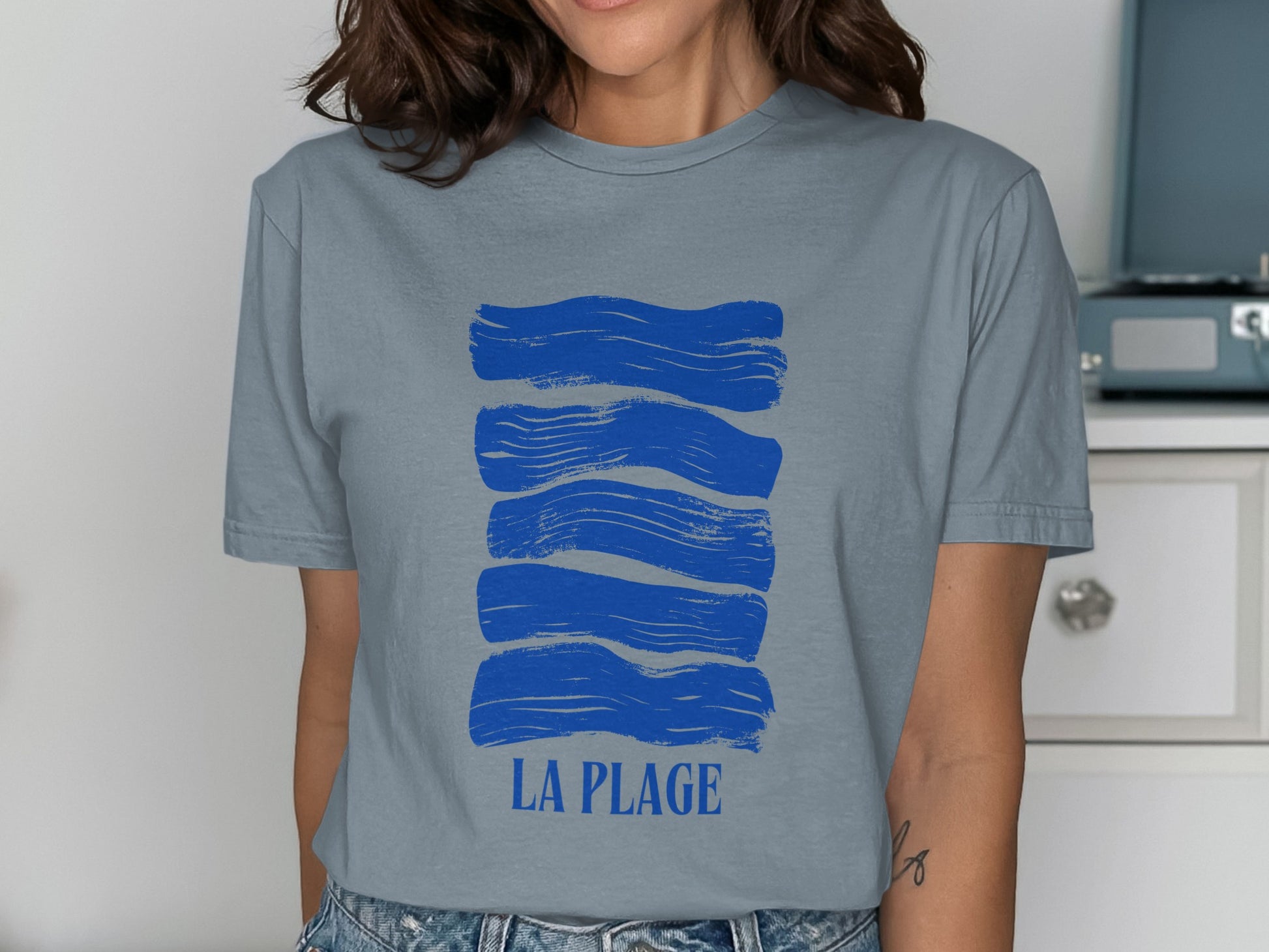 Blue abstract waves graphic with "LA PLAGE" text on a gray t-shirt.