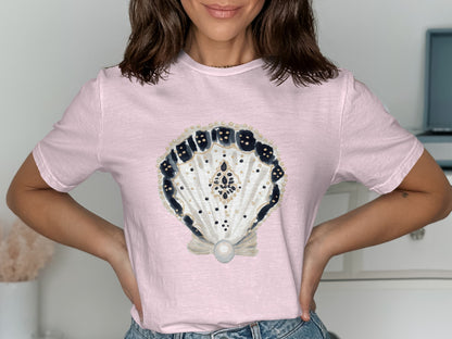 Pink t-shirt with a decorative seashell and pearl graphic.