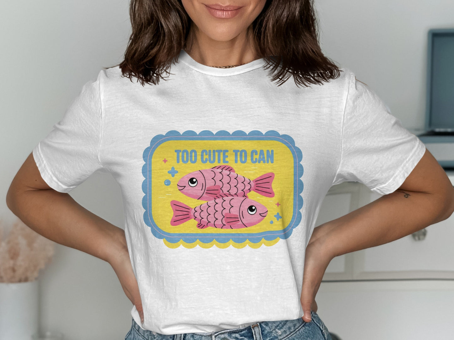 White t-shirt with cartoon fish and text "TOO CUTE TO CAN".
